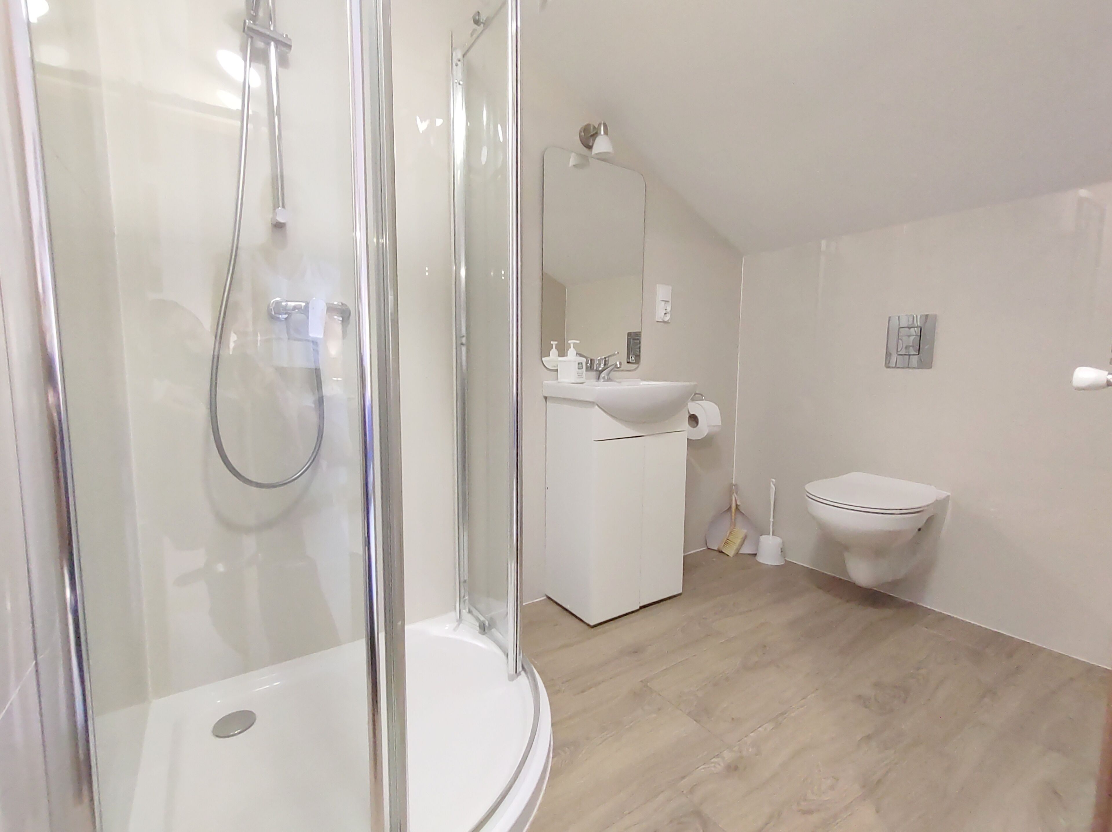 A modern bathroom with a glass-enclosed shower, a sink with a mirror, and a toilet.