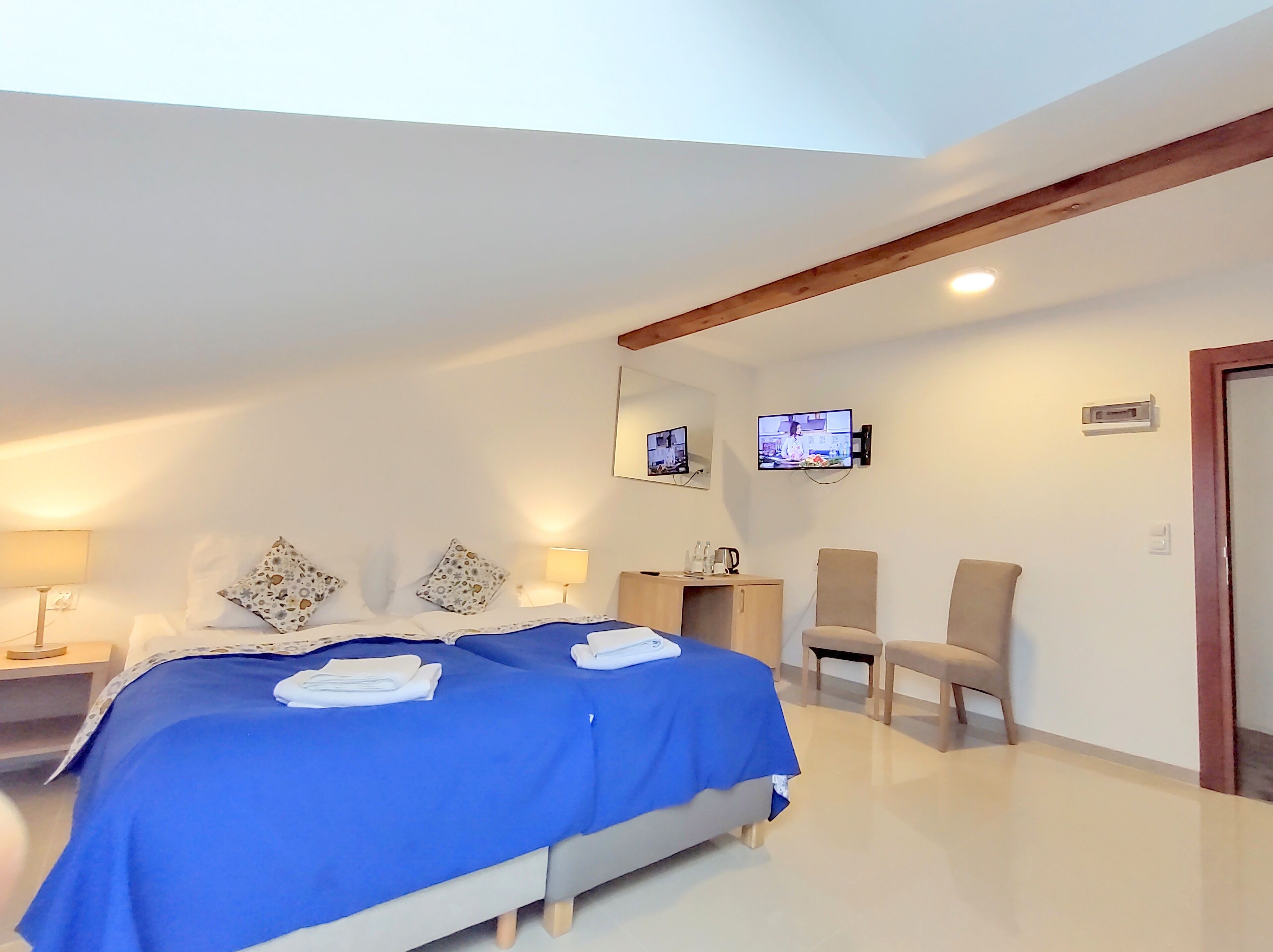 Une chambre d’hôtel avec un grand lit, deux tables de chevet, une télévision et un bureau avec une chaise.