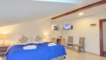 Une chambre d’hôtel avec un grand lit, deux tables de chevet, une télévision et un bureau avec une chaise.