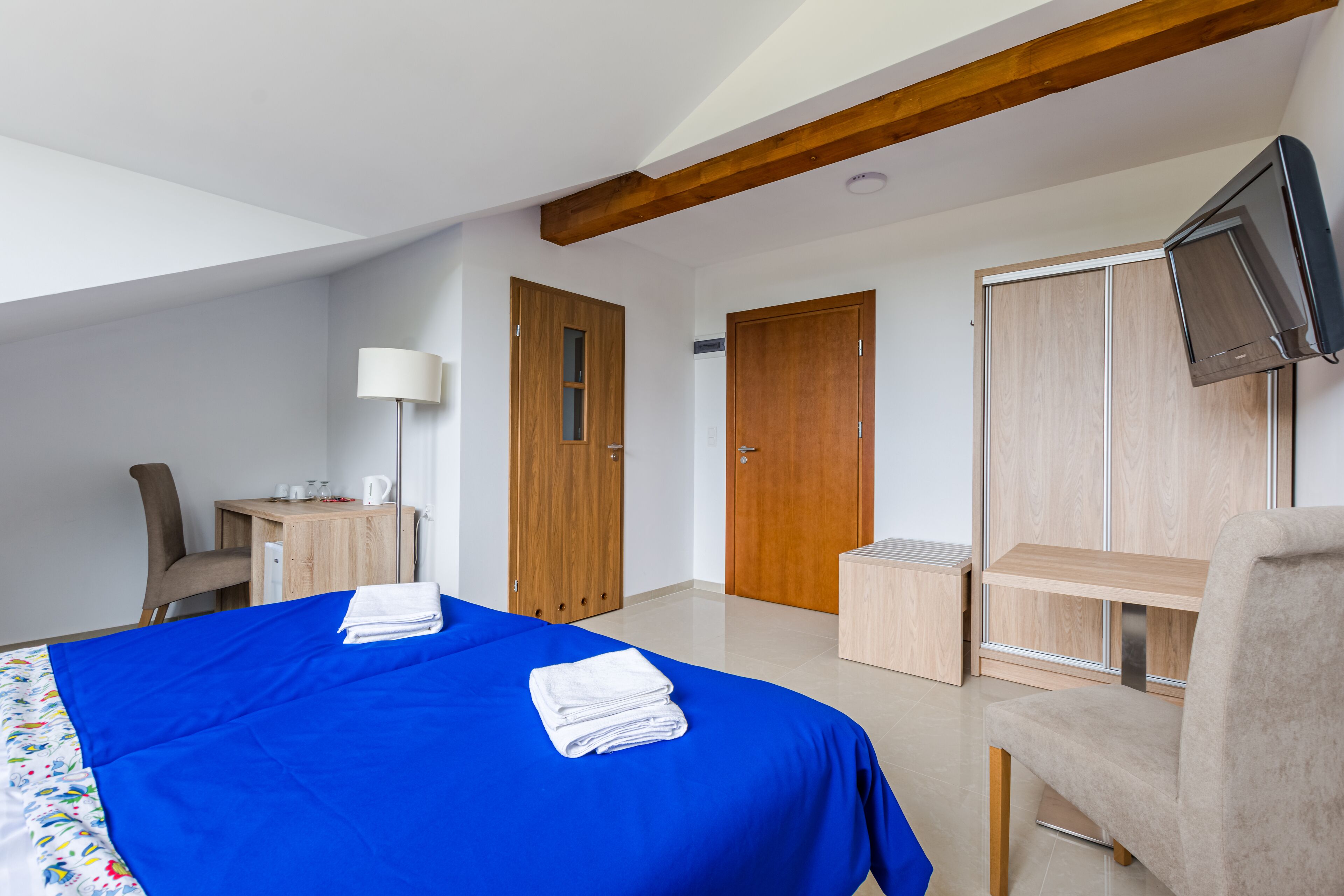 Ein Hotelzimmer mit Bett, Schreibtisch, Stuhl, Fernseher und Schränken.