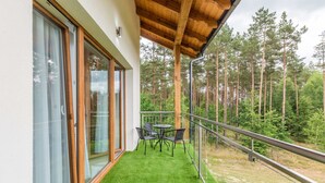 A balcony with a wooden ceiling, a glass door, and a table with chairs. - Źródlo Raduni (gmina Stezyca)