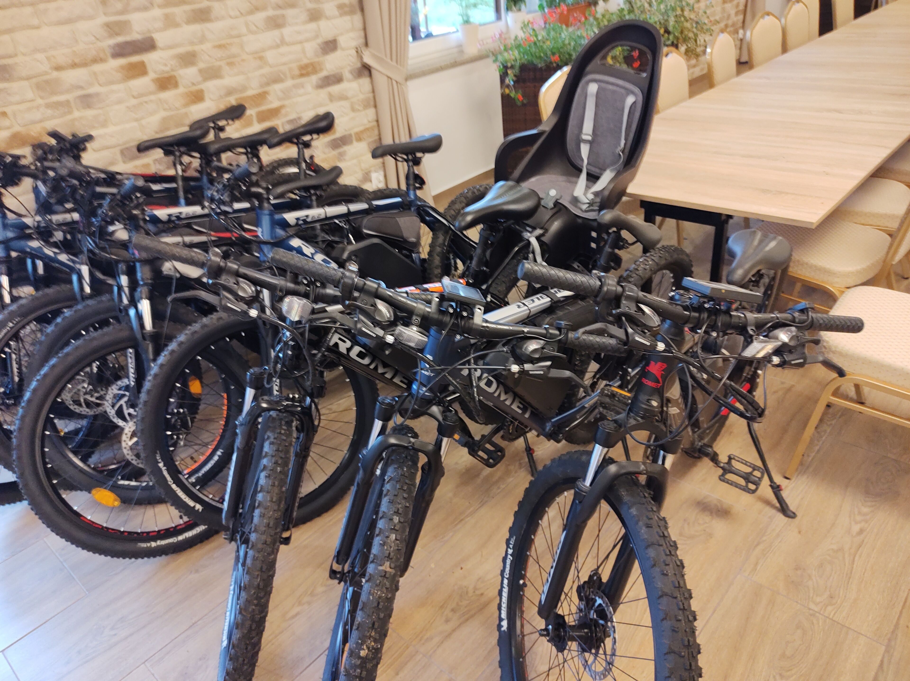 A room with a long wooden table and several bicycles parked against the wall.