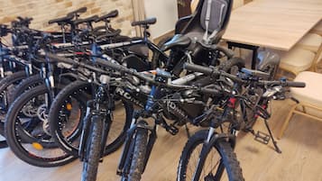 A room with a long wooden table and several bicycles parked against the wall.