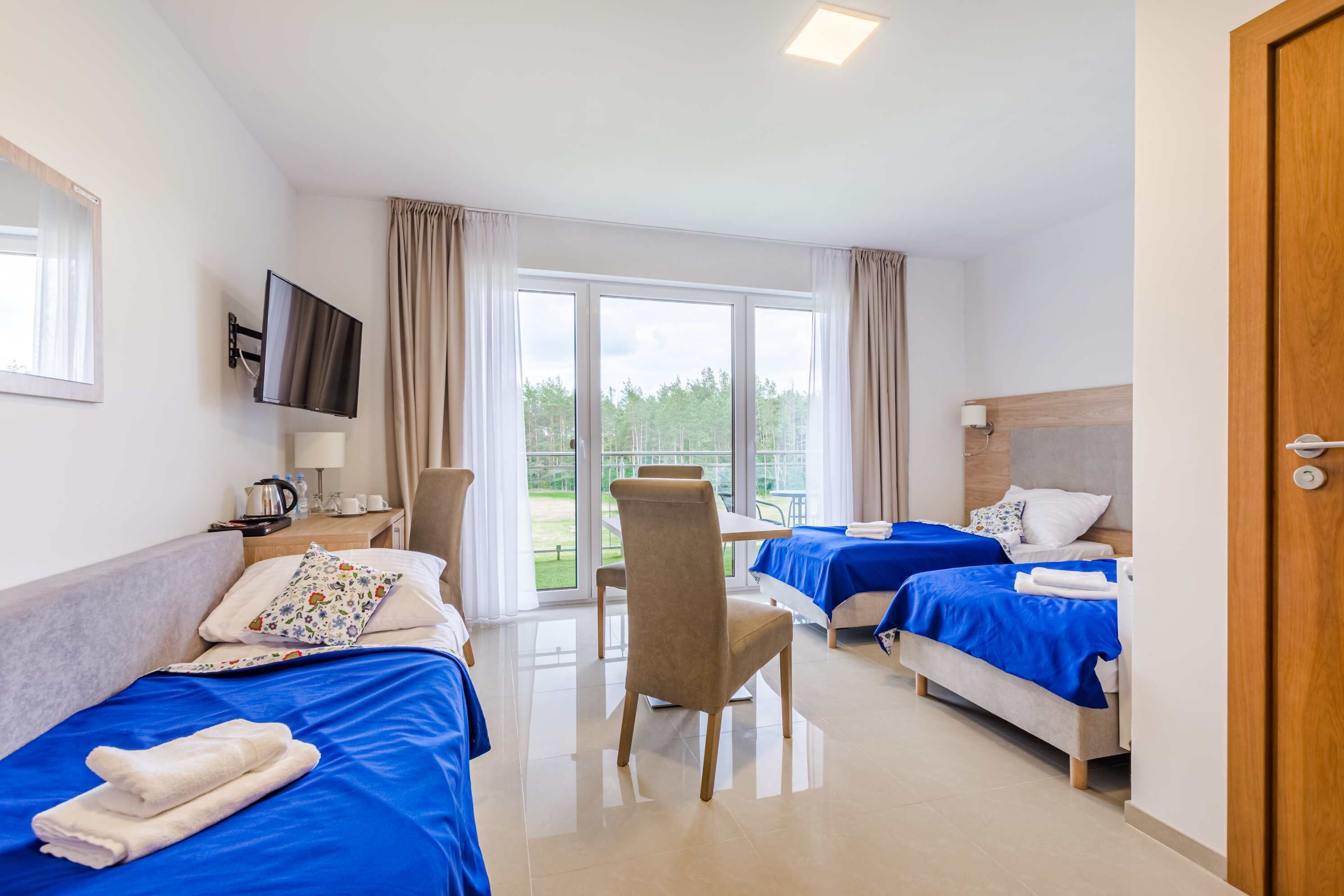 Quarto de hotel com duas camas, televisão, escrivaninha e cadeira.