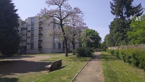 A pathway leading to a building with multiple floors and balconies, surrounded by trees and greenery. - Résidence du Parc des Tilleuls de LYON (4 bdrms, 82m²,free pkg, EUREXPO) (Lyon)