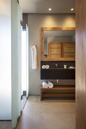 Une salle de bain moderne avec un meuble-lavabo en bois, un grand miroir et des serviettes soigneusement pliées.