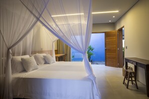 Une chambre avec un lit, une table de chevet, un bureau en bois et une vue sur la plage.