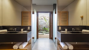A modern bathroom with two sinks, wooden cabinets, and a view of a stone wall and plants. - Lux & Modern Villa w/ 5 bedrooms in Trancoso (BA)