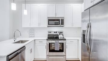 A modern kitchen with white cabinets, stainless steel appliances, and a dishwasher.