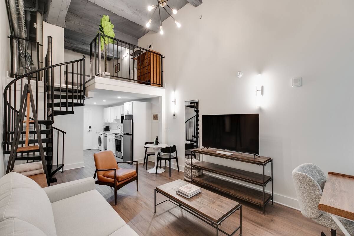 Ein modernes Wohnzimmer mit Treppe, Flachbildfernseher und Essbereich.