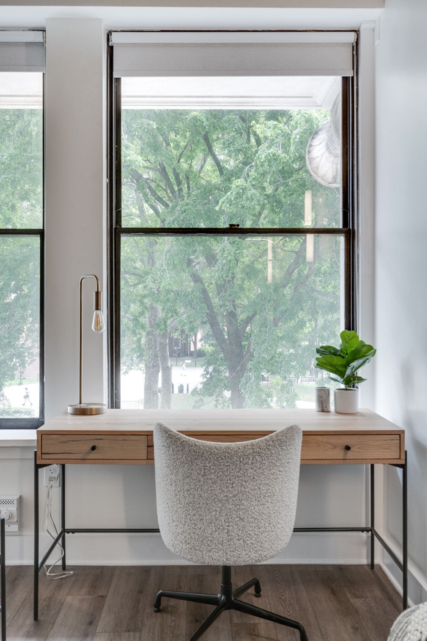 A modern office desk with a chair, a floor lamp, and a potted plant.