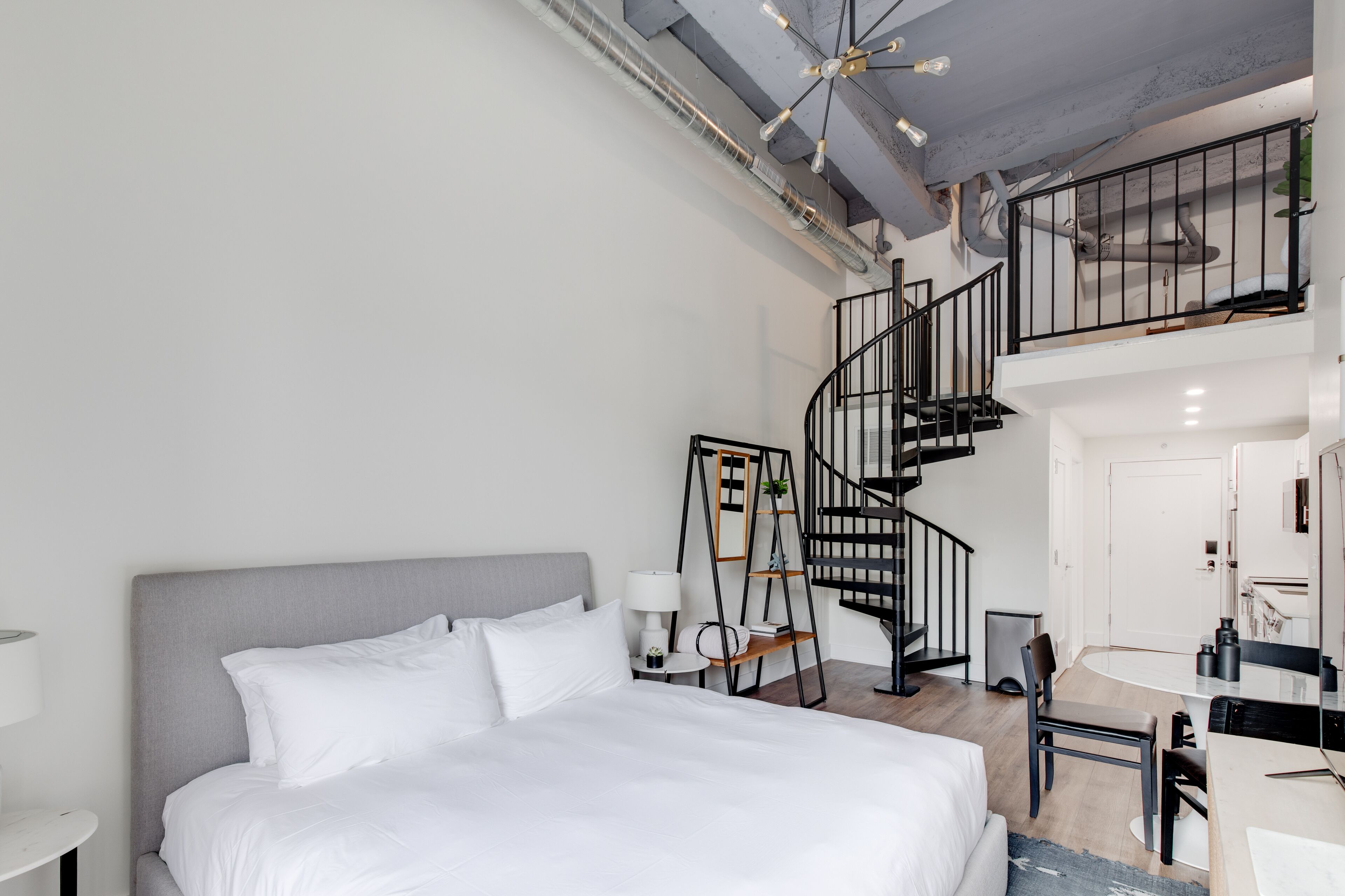 Una camera d'albergo moderna con un letto grande, una scrivania e una scala a chiocciola.