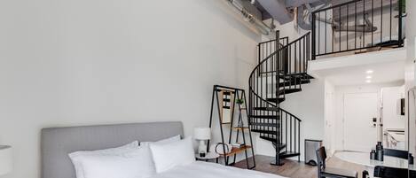 Una camera d'albergo moderna con un letto grande, una scrivania e una scala a chiocciola.