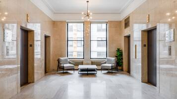 A spacious lobby with two elevators, a central coffee table, and large windows.