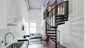 Una cocina moderna con un lavamanos integrado y una escalera con barandilla de metal.