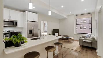 A modern kitchen with white cabinetry, stainless steel appliances, and a central island with stools.