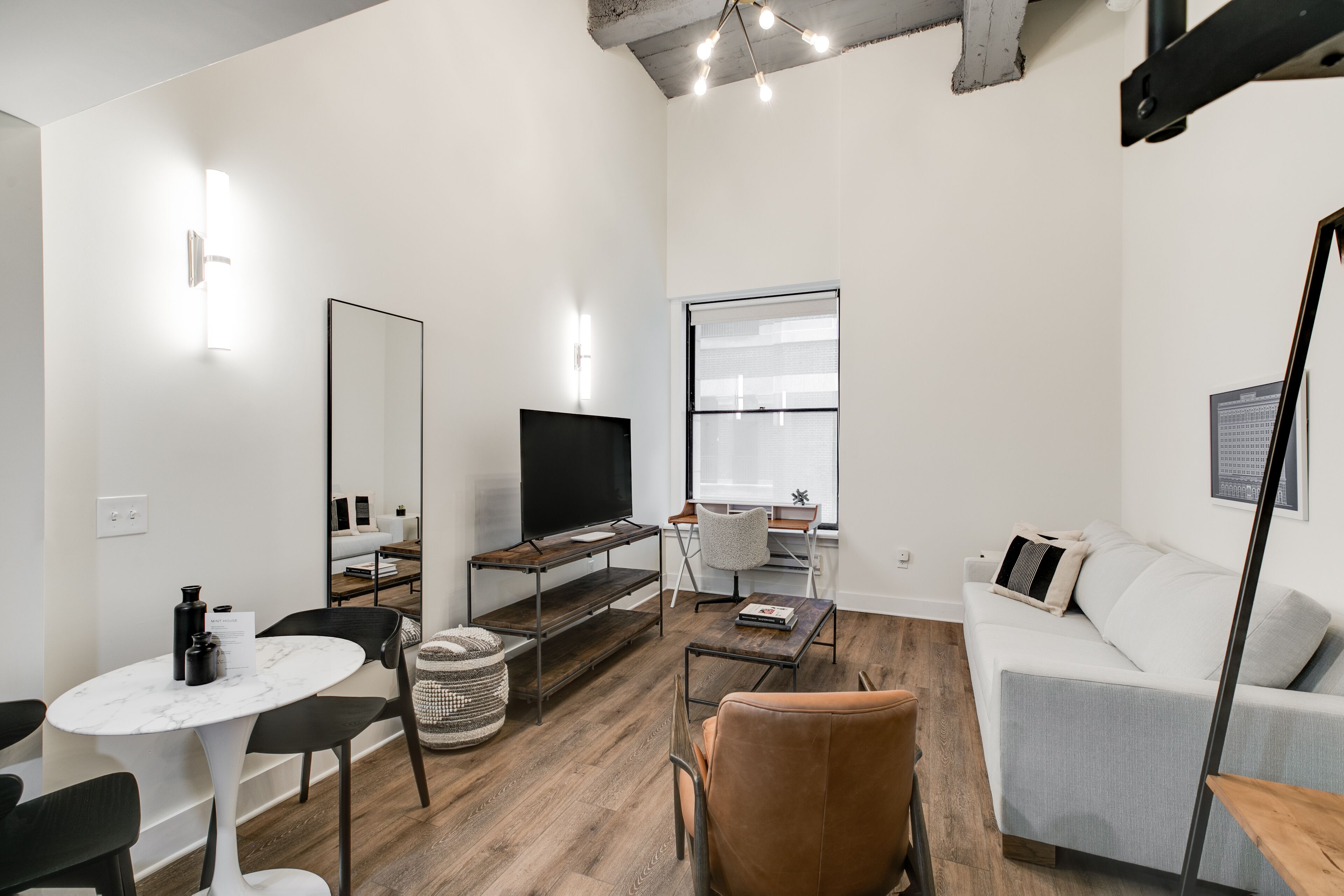 Een moderne woonkamer met een flatscreen televisie, een bank, een salontafel en een eethoek met een tafel en stoelen.