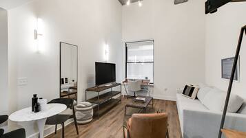Een moderne woonkamer met een flatscreen televisie, een bank, een salontafel en een eethoek met een tafel en stoelen.
