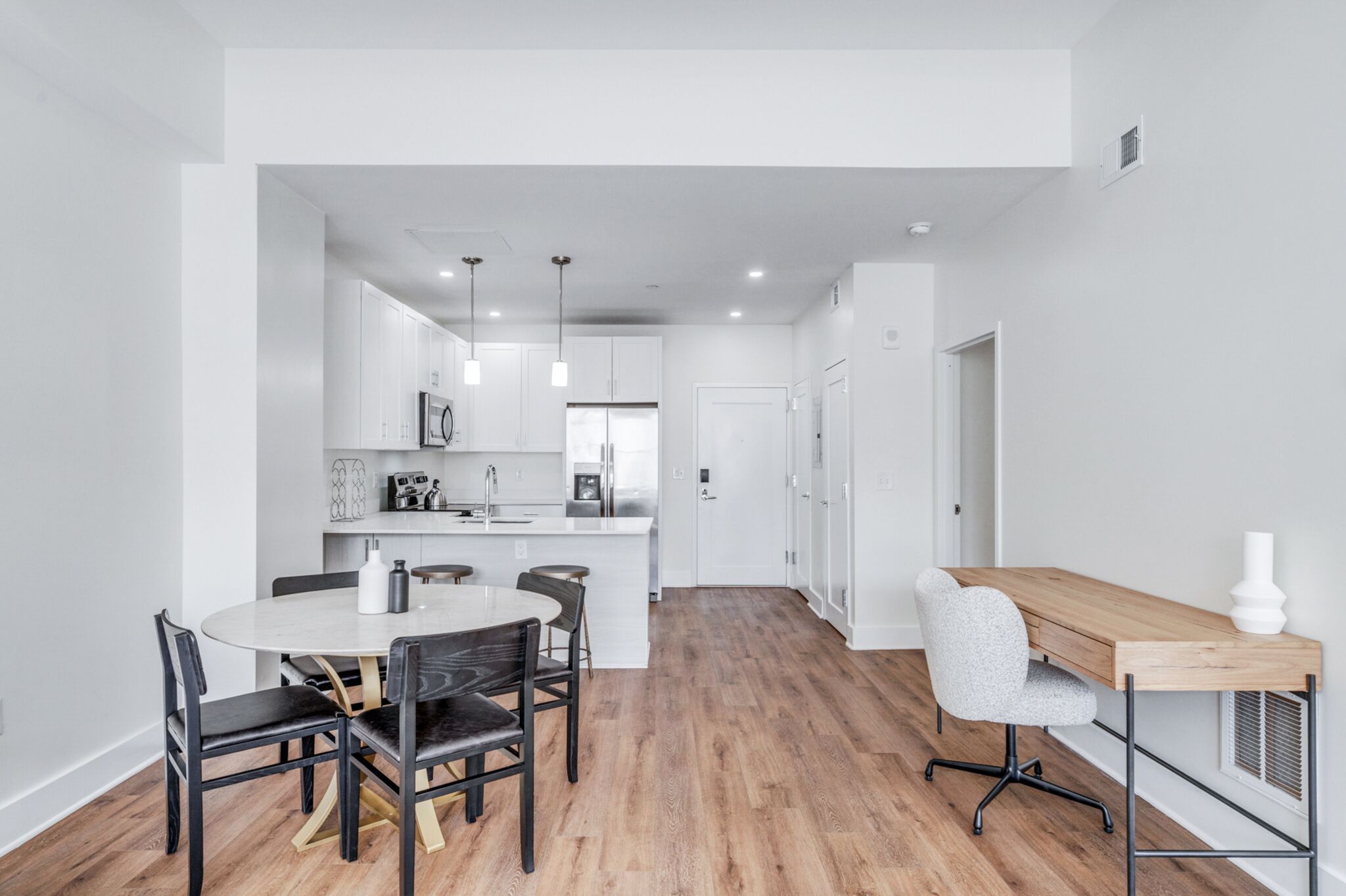 A modern kitchen with white cabinets, a central island, and pendant lighting.