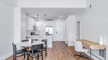 A modern kitchen with white cabinets, a central island, and pendant lighting.