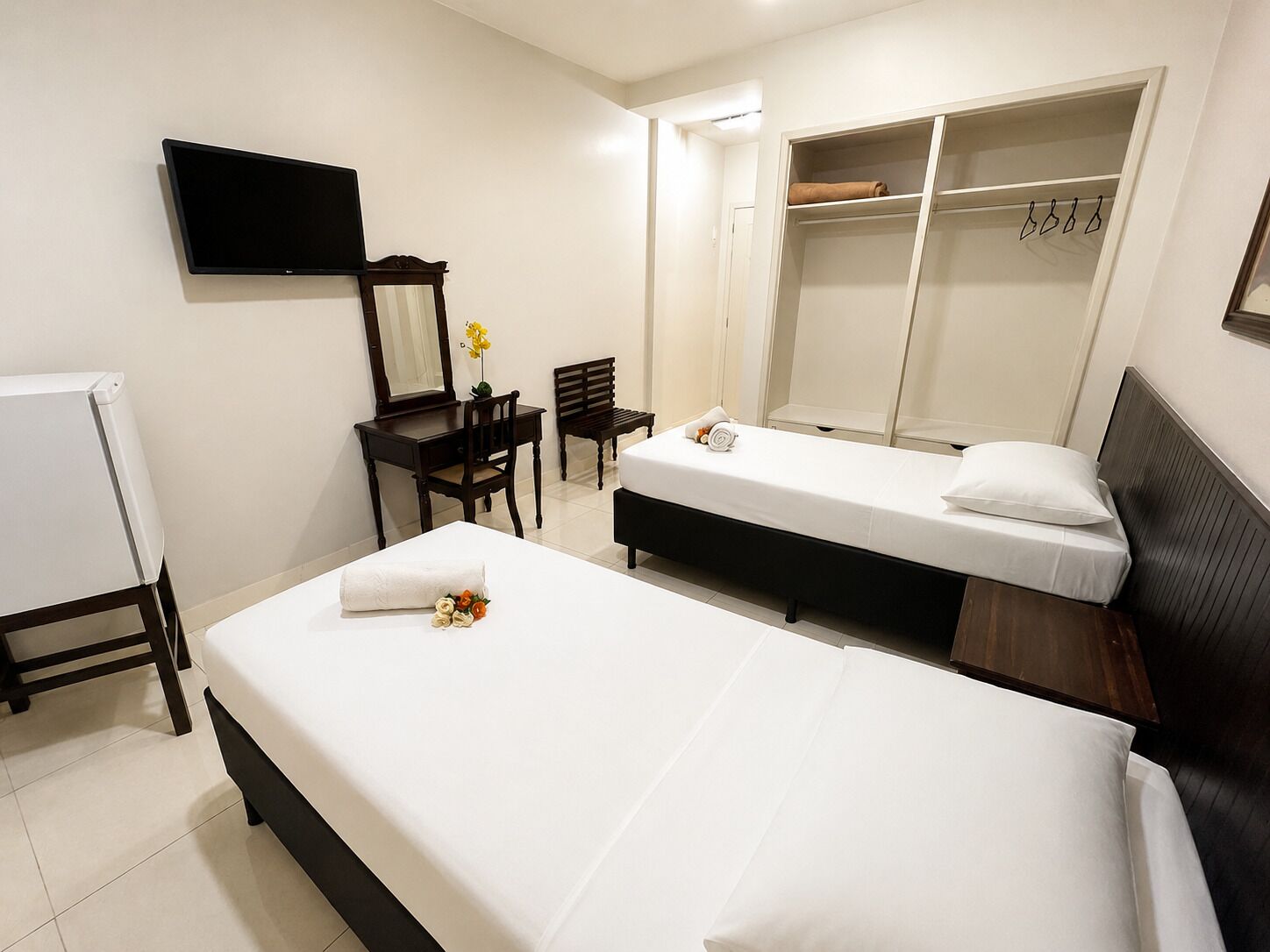 Ein Hotelzimmer mit zwei Betten, einem Schreibtisch, einem Stuhl, einem Fernseher und einem Kleiderschrank.