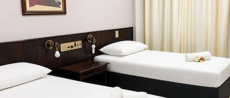 Habitación de hotel con dos camas, una mesita de noche, una lámpara de pared y un cuadro.