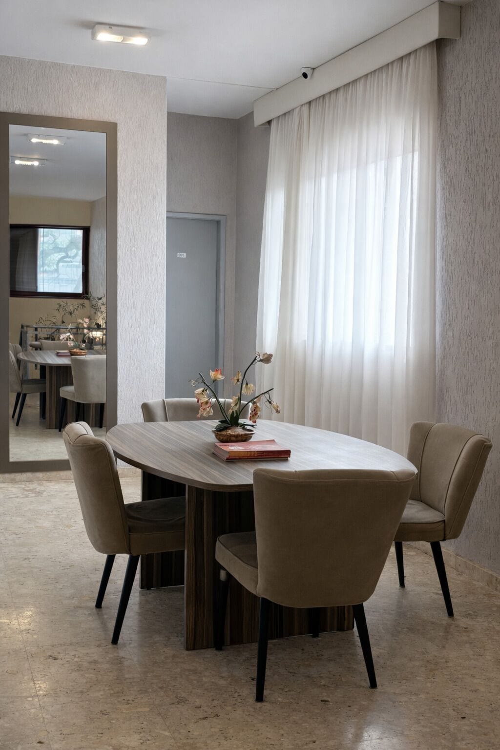 Un comedor moderno con una mesa redonda, cuatro sillas y un jarrón de flores.