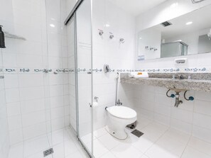 A modern bathroom with a glass shower enclosure, a white toilet, a marble sink with a soap dispenser, and a mirror above the sink. - Athus Hotel by Bsb Inn (Brasília)