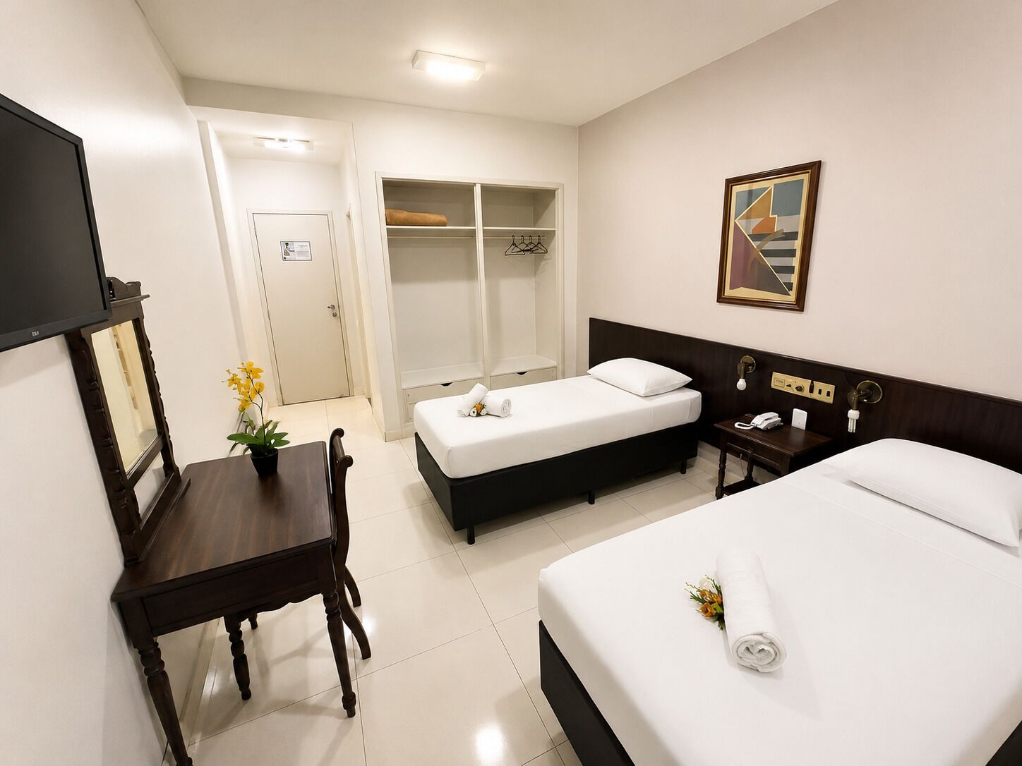 A hotel room with a bed, a desk, a wardrobe, and a television.