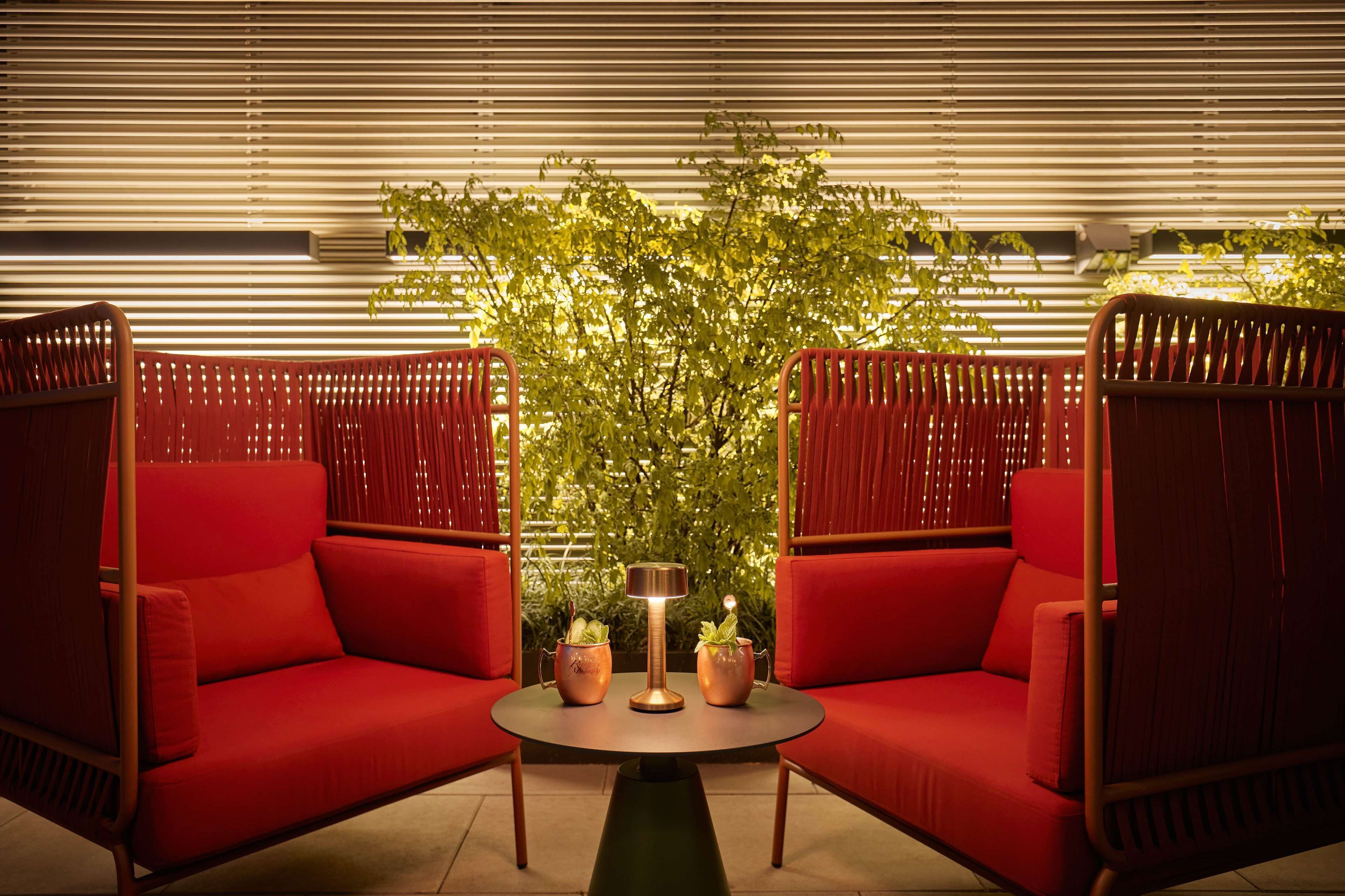 A red sofa set with a table in the center, surrounded by a bamboo fence and a potted plant.