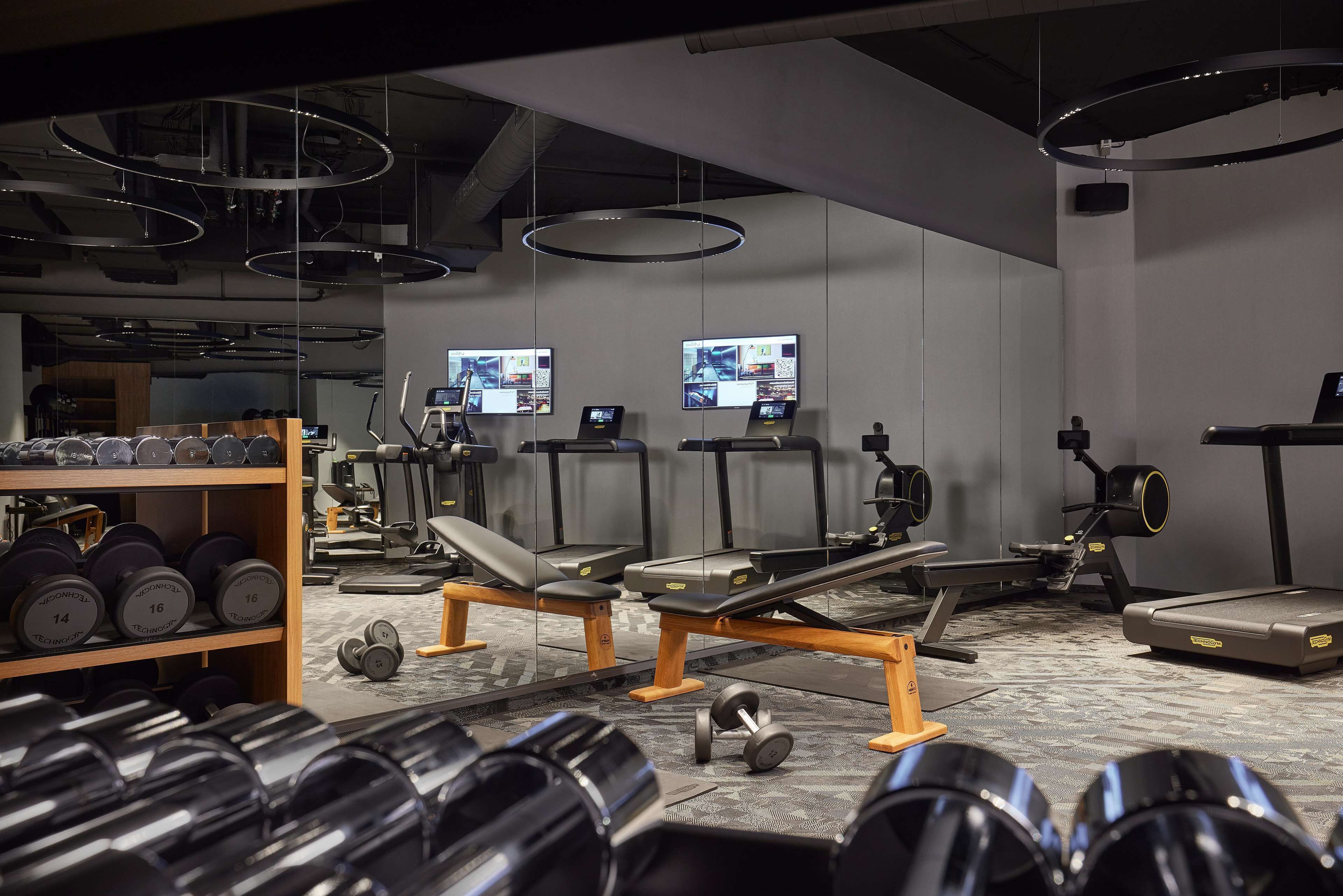 A gym with various exercise equipment, including treadmills, weight machines, and dumbbells.