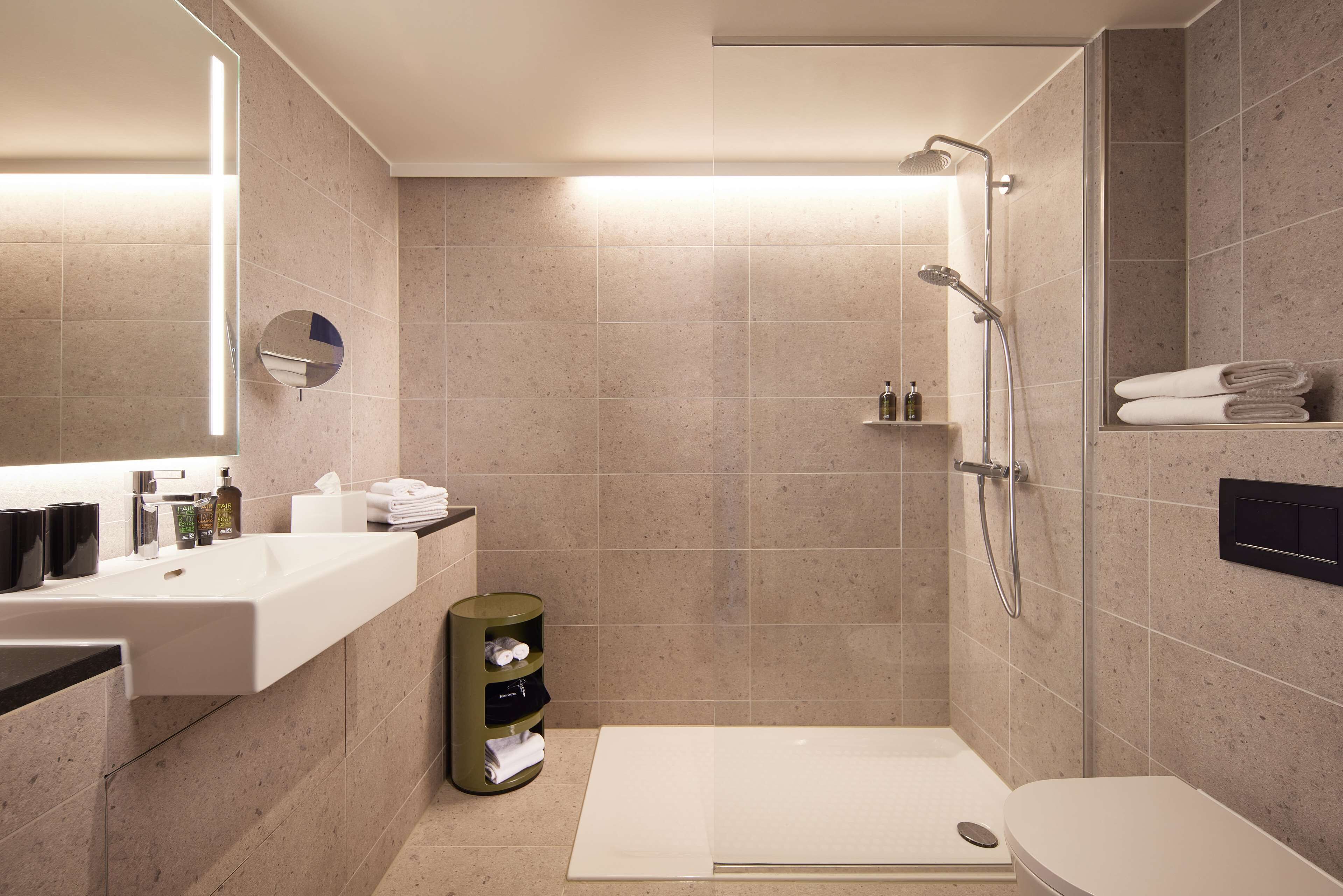 A modern bathroom with a shower, toilet, and sink.