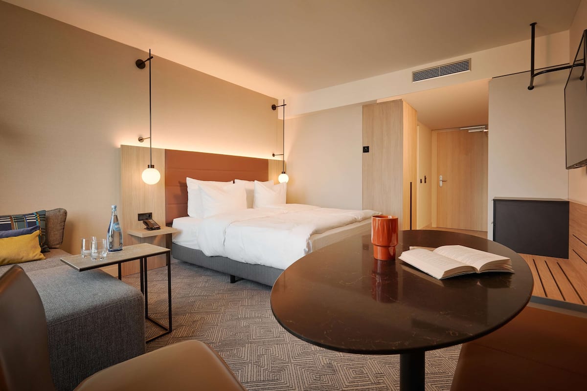 Une chambre d’hôtel avec un lit, une table de chevet et une table ronde sur laquelle se trouve un livre.