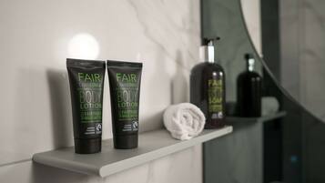 Two bottles of Fair CosmEthics body lotion on a white shelf in a bathroom.