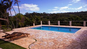 A rectangular swimming pool with a stone tile deck, surrounded by a metal railing. - Chacara Giovaninha, located in Serra dos Cocais.  (Valinhos)