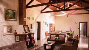 A cozy living room with a fireplace, leather sofas, and a dining area with a wooden table and chairs. - Chacara Giovaninha, located in Serra dos Cocais.  (Valinhos)
