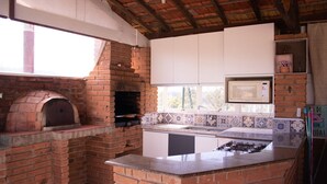 A kitchen with a brick oven, white cabinets, a microwave, and a gas stove. - Chacara Giovaninha, located in Serra dos Cocais.  (Valinhos)