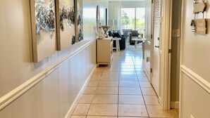 Un couloir doté d’un sol carrelé, un comptoir d’accueil et une vue sur un balcon aménagé avec du mobilier d’extérieur.