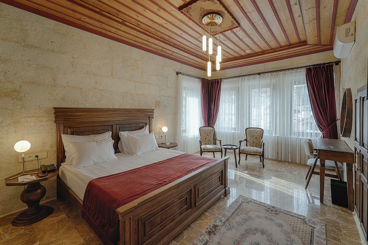 A spacious bedroom with a large wooden bed, a nightstand, a desk, and a chair.