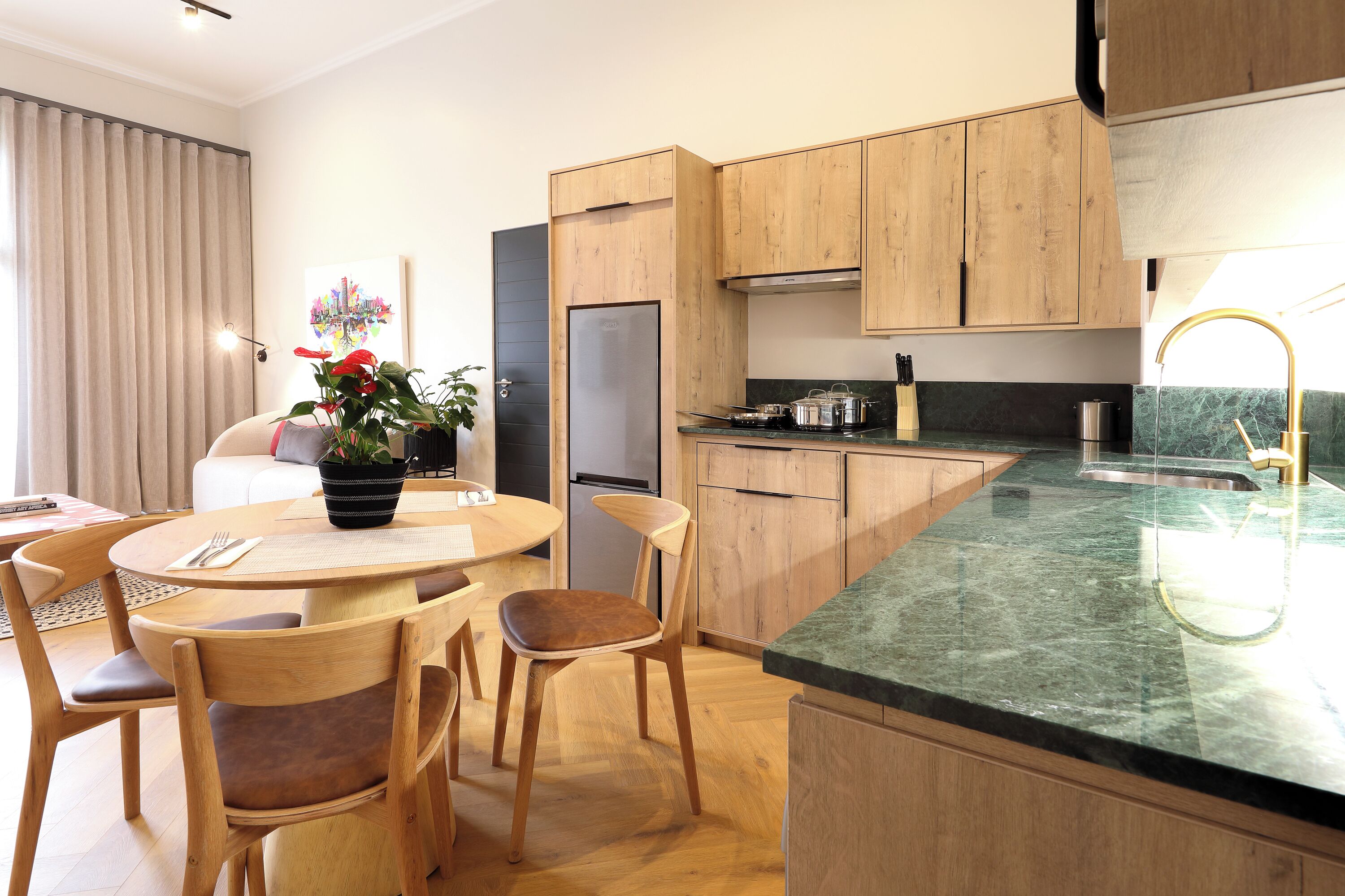 Une cuisine moderne avec des meubles en bois, un plan de travail en marbre et un coin repas comprenant une table ronde et des chaises.