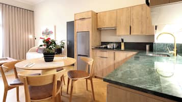 Une cuisine moderne avec des meubles en bois, un plan de travail en marbre et un coin repas comprenant une table ronde et des chaises.