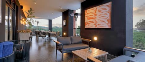 Een modern buitenverblijf met een bank, stoelen en een tafel, met een groot abstract schilderij en uitzicht op het landschap.