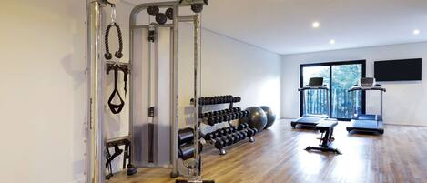 A gym with exercise equipment, dumbbells, and treadmills.