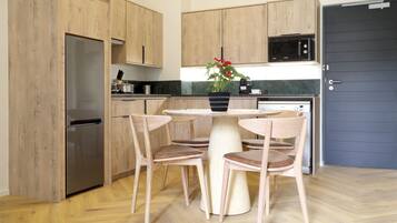 Une cuisine moderne avec des meubles en bois, un réfrigérateur en acier inoxydable, un four à micro-ondes et une table à manger avec quatre chaises.