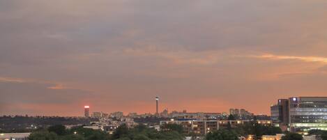 A cityscape at dusk with a prominent tower and modern buildings.