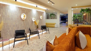 A modern lobby with a seating area, a reception desk, and a plant wall.