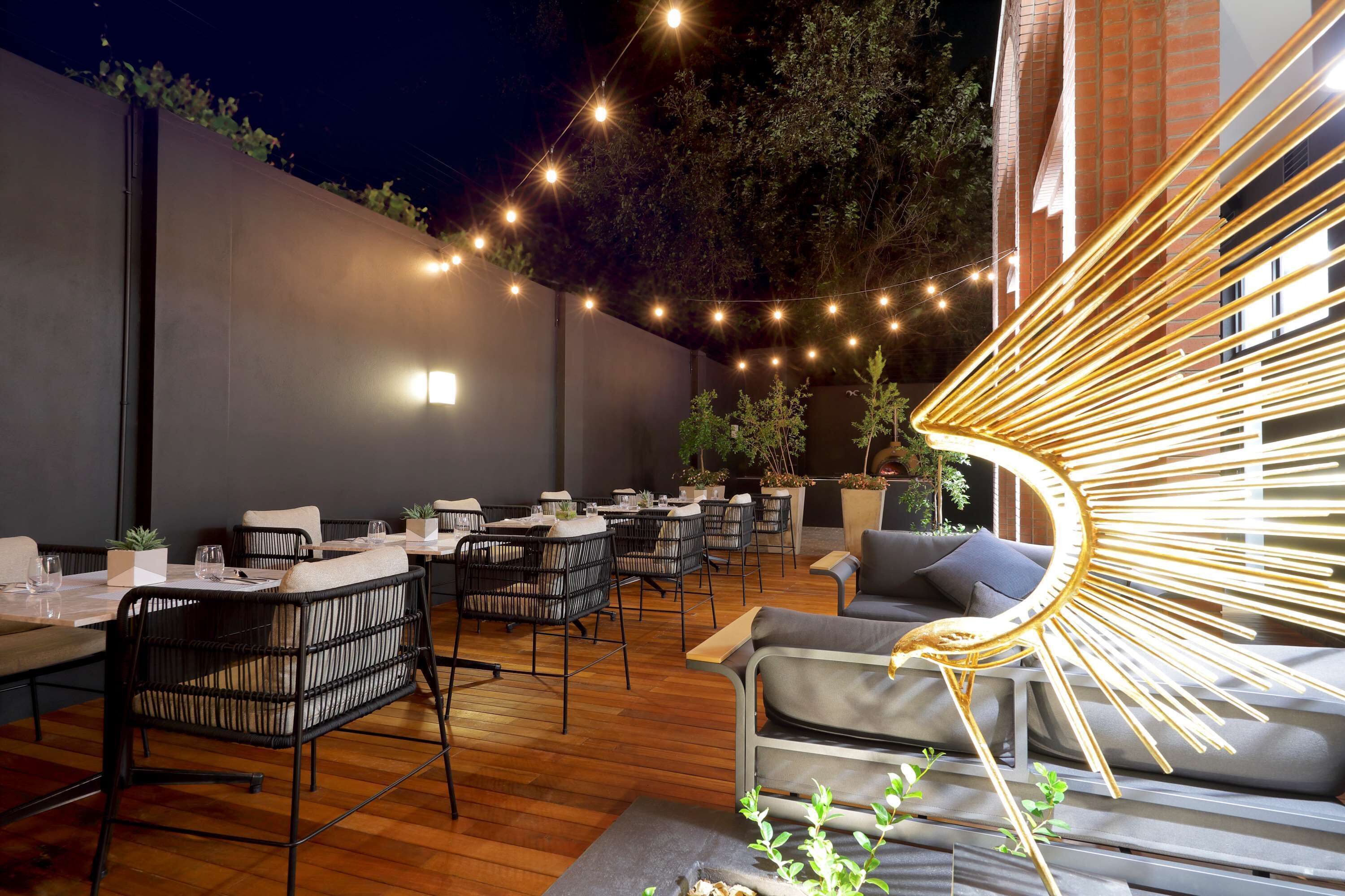 An outdoor dining area with tables and chairs, string lights, and a sofa.