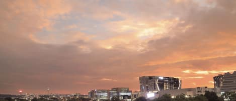 A cityscape at dusk with modern buildings and a prominent tower.