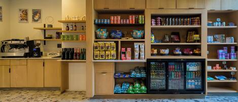 A coffee shop interior with a coffee machine, shelves stocked with snacks, and a refrigerated display.