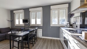 Eine moderne Küche mit Essbereich, großen Fenstern und einem eingebauten Backofen.